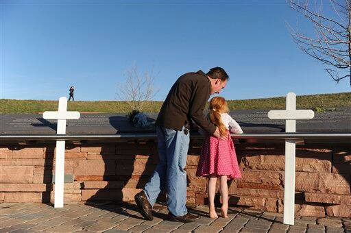 Wade Abram and his 5-year-old daughter Mimi visit the Columbine High School memorial at Clement Park, near Littleton, Colo., on Sunday, April 19, 2009 prior to a candlelight vigil.