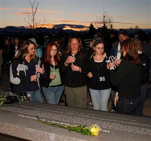 The family of slain school teacher Dave Sanders gathers at his memorial plaque for a candlelight vigil at the Columbine High School Memorial at Clement Park, near Littleton, Colo., on Sunday, April 19, 2009 on the eve of the 10th anniversary of the massacre.