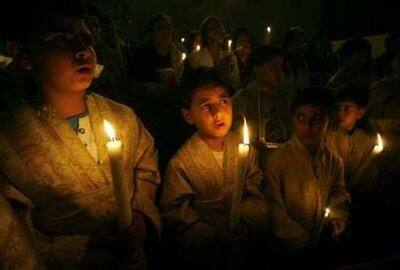 Palestinian Orthodox Christians hold candles during Easter Mass at al-Roum Church in Gaza City early April 19, 2009