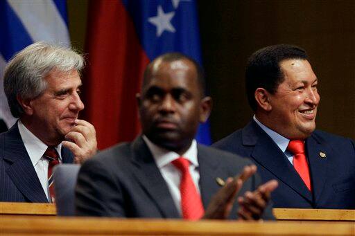 Venezuela`s President Hugo Chavez, right, smiles, as he sits near Dominica`s Prime Minister Roosevelt Skerrit, center, and Uruguay`s President Tabare Vasquez, during the opening session of the 5th Summit of the Americas in Port of Spain, Trinidad and Tobago, Friday April 17, 2009.