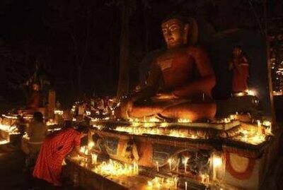 Devotees light candles in front of a Buddha statue to mark the Nepalese New Year 2066 at a temple in Kathmandu.