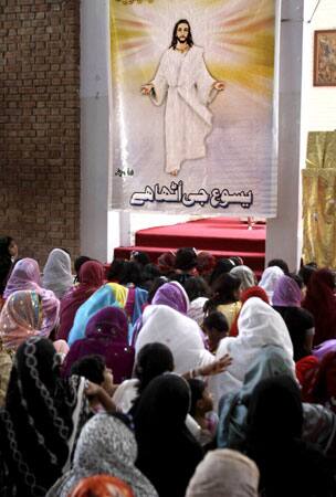 Pakistani Christians pray next to a poster of Jesus Christ during the Easter mass at a Catholic church in Peshawar, Pakistan, on Sunday, April 12, 2009.