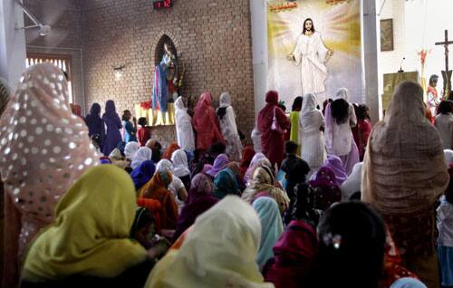 Pakistani Christians pray next to a poster of Jesus Christ during the Easter mass at a Catholic church in Peshawar, Pakistan, on Sunday, April 12, 2009.