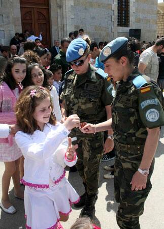 A Spanish U.N peacekeeper soldier, breaks colored Easter eggs with a Lebanese girl outside a Church in Marjayoun village, southeast of Lebanon, on Sunday, April 12, 2009.