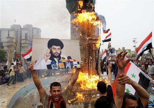 Supporters of anti-U.S. Shiite cleric Muqtada al-Sadr, seen in a poster at left, burn an effigy representing former U.S. President George W. Bush in central Baghdad.