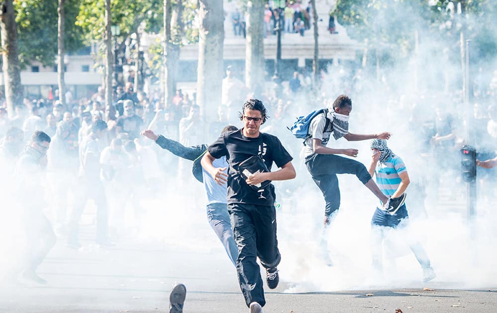 Pro-Palestinian protesters try to escape from a tear gas cloud thrown by riot police during a banned demonstration in support of Gaza at Place de la Republique in Paris, France.