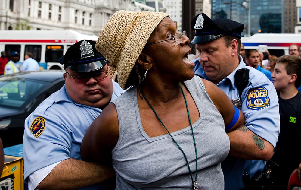 Police detain a woman who was swinging her cane at a demonstrator, not pictured, who was supporting Israel in its war with Hamas members in the Gaza Strip, during a rally at John F. Kennedy Plaza, also known as Love Park, in Philadelphia.