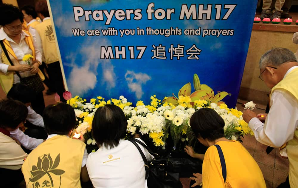 People place flowers after a special prayer for the victims of the crashed Malaysia Airlines Flight 17, in Kuala Lumpur, Malaysia.