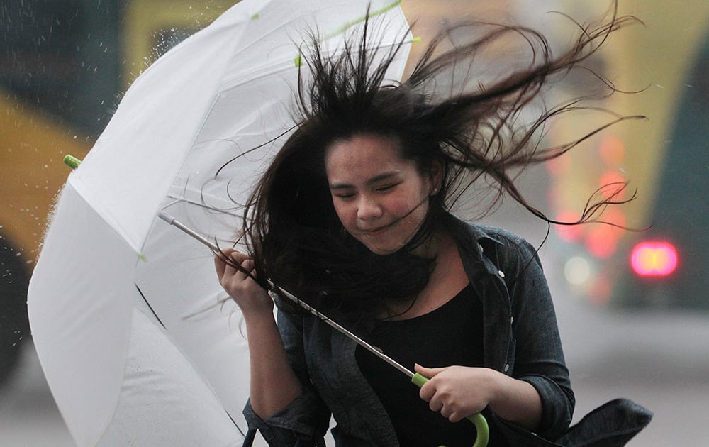 A woman struggles with her umbrella in strong winds and rain from approaching Typhoon Matmo in Taipei, Taiwan.