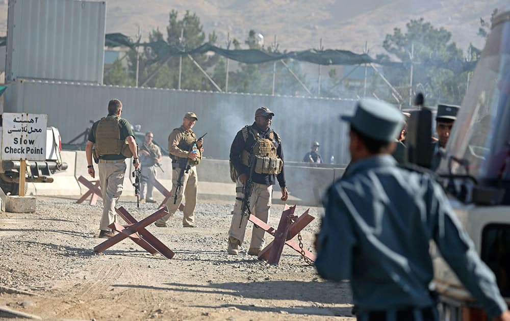 Afghan and foreign security forces inspect the site of a suicide attack at the deputy counter narcotic compound in Kabul, Afghanistan.