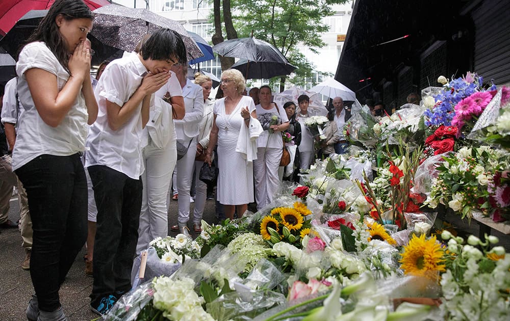 People react as they look at flowers placed in front of the Asian Glories restaurant, after a walk to commemorate victims of Flight 17 in Rotterdam.