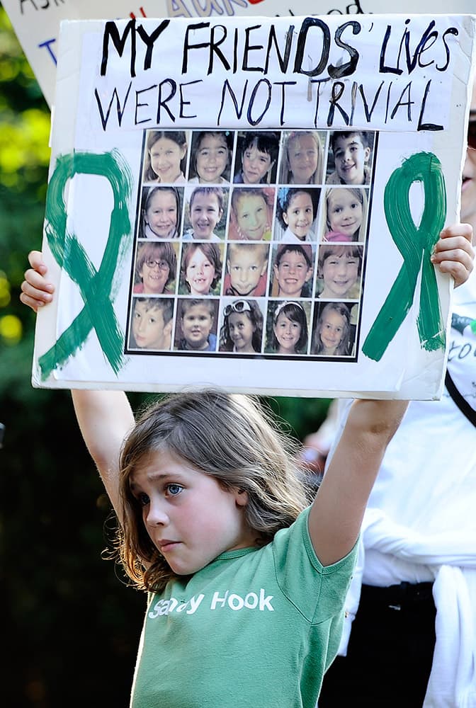 Marie Morosky, of Newtown, Conn. holds up a sign with images of the children killed in the Sandy Hook School shooting outside a fundraising event for Republican gubernatorial candidate Tom Foley with New Jersey Gov. Chris Christie at a private residence,  in Greenwich, Conn. 