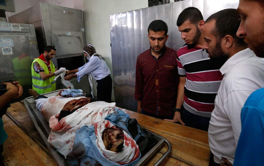 Palestinians gather around the body of Ahmed Barnasawi, 22, at the Shifa hospital`s morgue as workers prepare him for burial, in Gaza City.