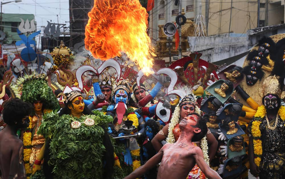 An Indian artist performs with fire during a procession as part of 