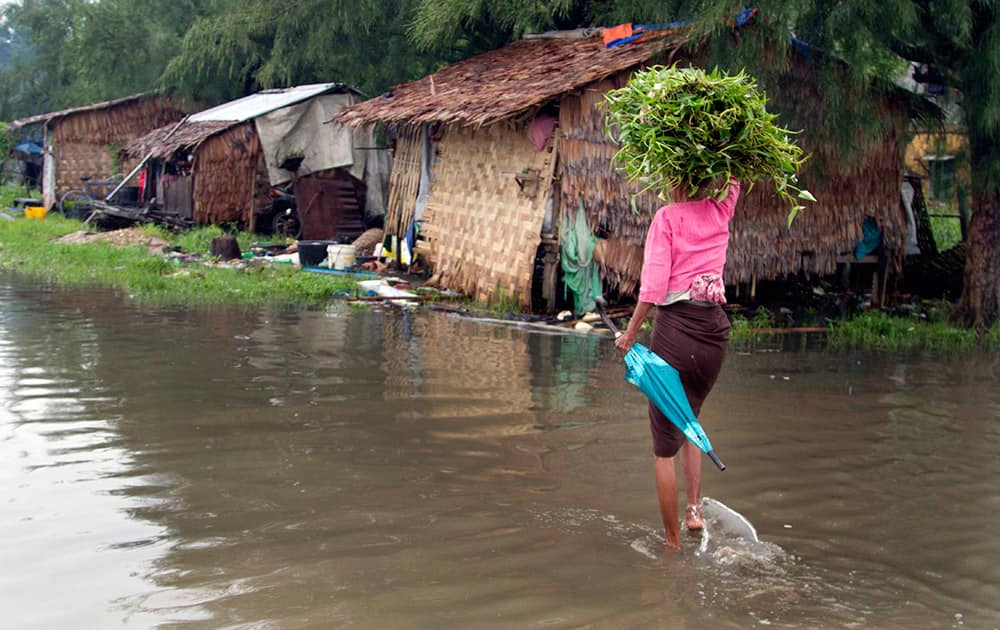 A woman carries water-cress as she wades through a flooded road following heavy rains in outskirts of Yangon, Myanmar.