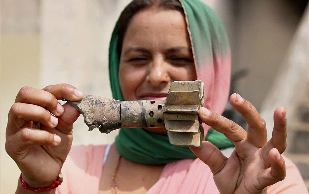 A woman shows a mortar shell recovered from a residential area after it was allegedly fired from Pakistan`s side in Gharna village at the India-Pakistan International border in RS Pura sector about 40 km from Jammu.