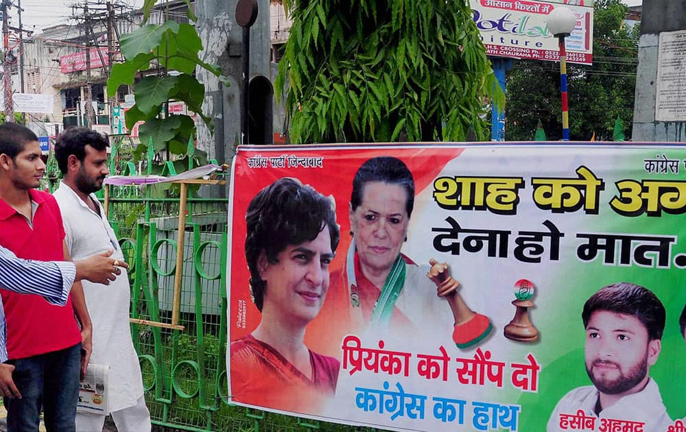 People look at a banner put up by Congress workers urging to induct Priyanka Gandhi Vadra into party leadership in Allahabad.