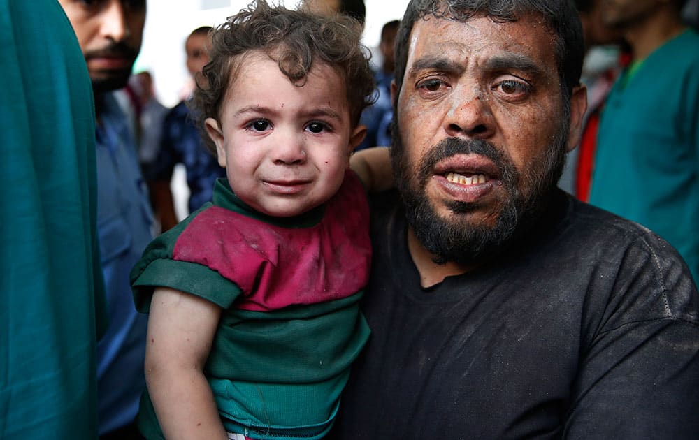 A Palestinian carries a wounded boy in the emergency room of Shifa hospital in Gaza City, northern Gaza Strip.