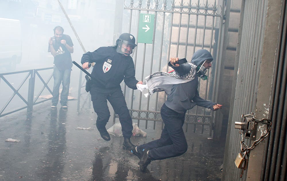 A riot police officer reacts with a pro-Palestinian demonstrator, during a demonstration in Paris.