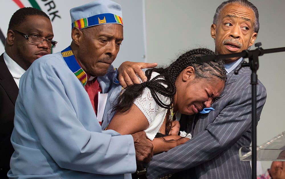 Esaw Garner, center, wife of Eric Garner, breaks down in the arms of Rev. Herbert Daughtry and Rev. Al Sharpton, right, during a rally at the National Action Network headquarters for Eric Garner, in New York.