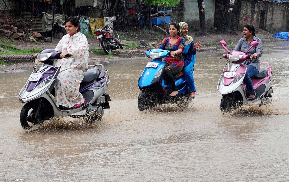 Girls riding scooters during rains in Allahabad.