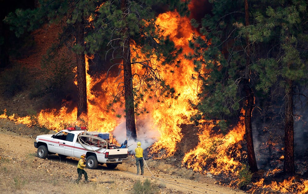 A firefighter cools a tree in a line of fire in Winthrop, Wash.