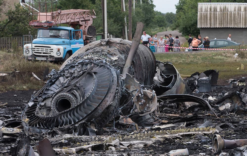 Local citizens, background, look at the site of a crashed Malaysia Airlines passenger plane near the village of Rozsypne, Ukraine, eastern Ukraine.