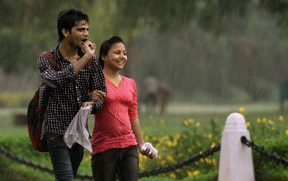 A couple enjoys the rain at Rajpath in New Delhi.