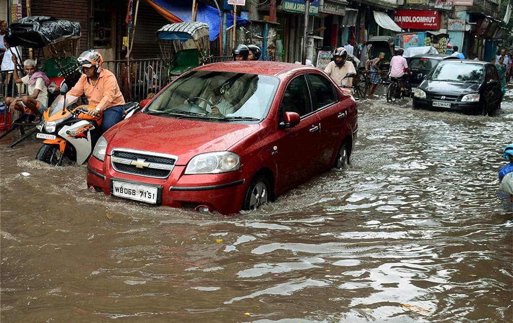 Vehicles move through a waterlogged road after heavy rains in Kolkata.