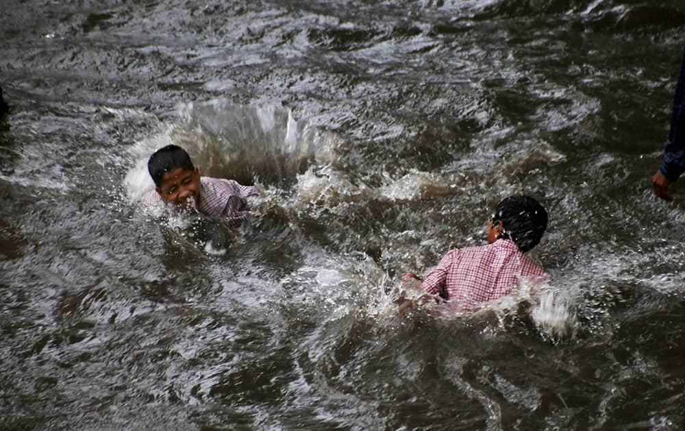 Children playing at a waterlogged road after heavy rains in Thane.