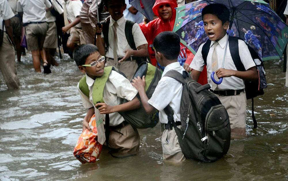 School children wading through a waterlogged street after heavy rains in Mumbai.