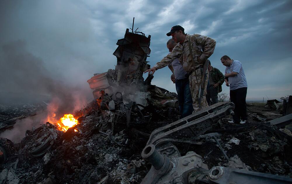 People inspect the crash site of a passenger plane near the village of Hrabove, Ukraine.