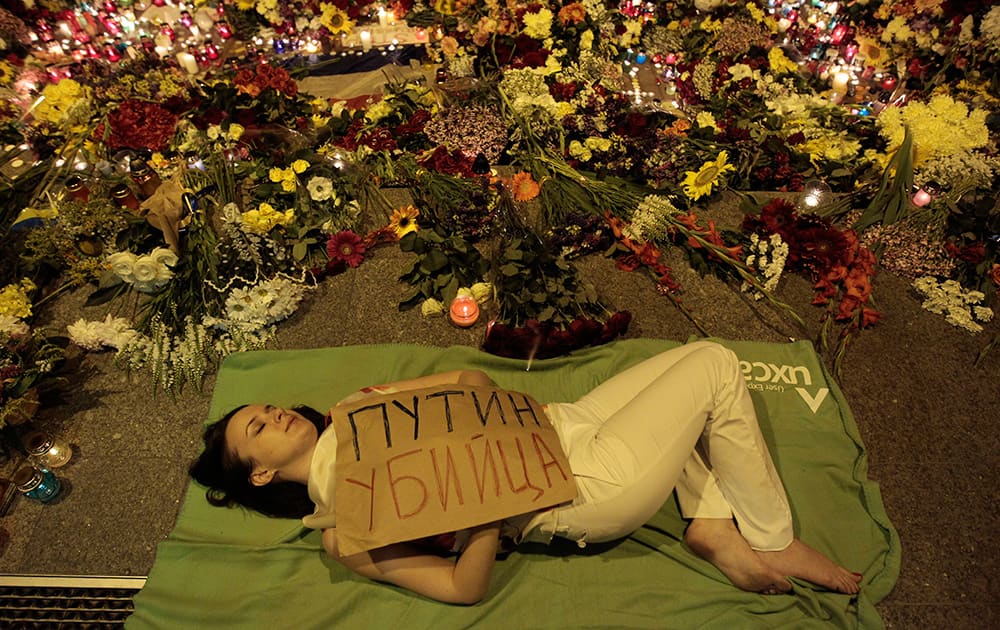 Ukrainian woman lies down in front of Dutch embassy holding a poster reading `Putin is a killer`, in Kiev,Ukraine.