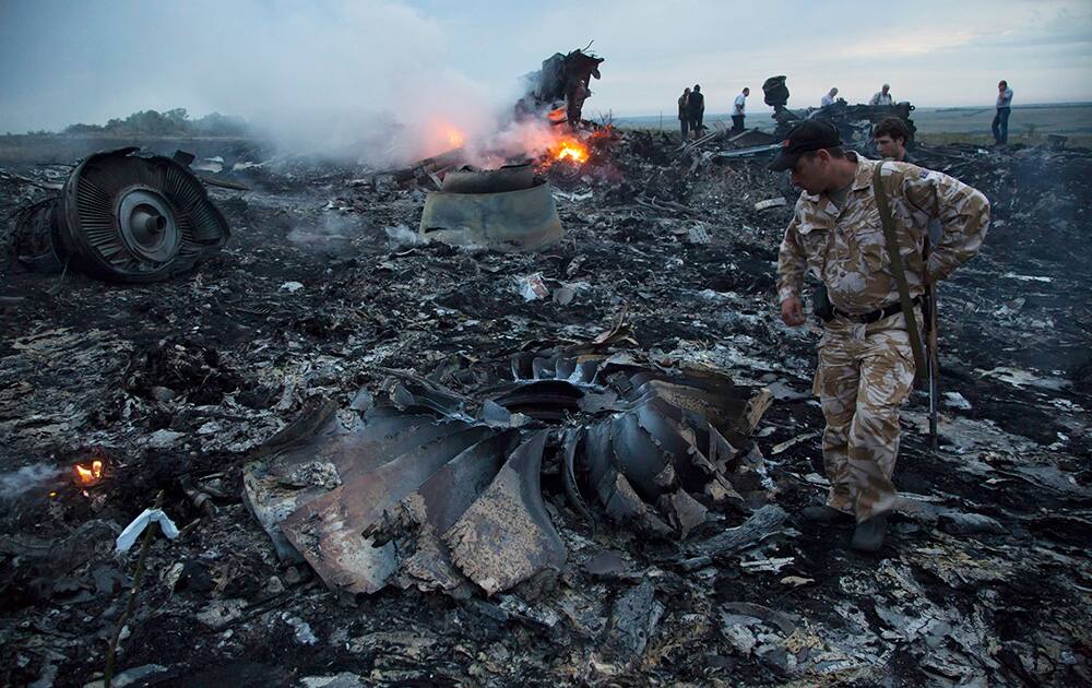 People walk amongst the debris at the crash site of a passenger plane near the village of Hrabove, Ukraine