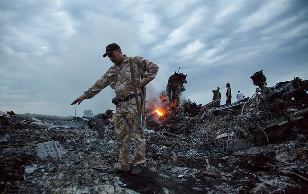 People walk amongst the debris at the crash site of a passenger plane near the village of Hrabove, Ukraine.