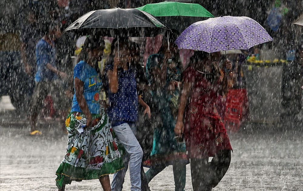 Young walk with umbrellas as it rains in Kolkata.