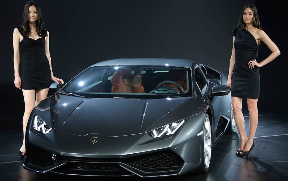 Models pose with a Lamborghini Huracan LP 610-4 during its launch event in Tokyo.