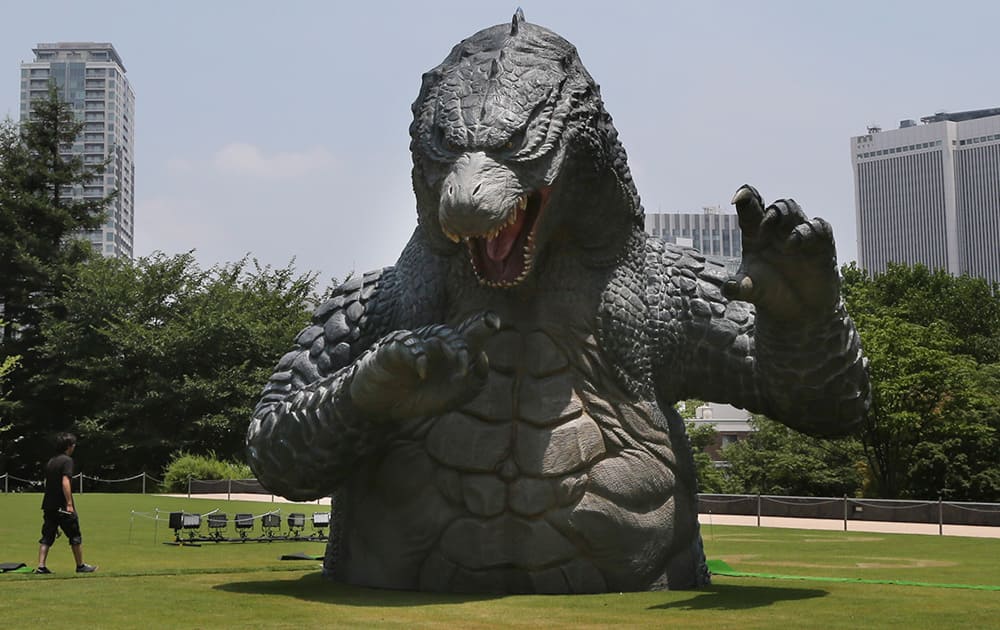 A scaled down model of the new `Godzilla,` dwarfs a worker at Tokyo Midtown in Tokyo. The model is being displayed to mark Hollywood`s `Godzilla` remake and the 60th anniversary of the first `Godzilla` movie. `Godzilla,` directed by Gareth Edwards, opens in Japan on July 25. 