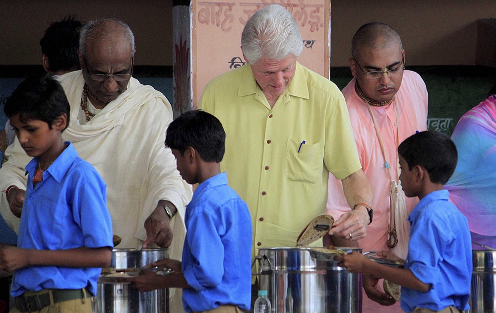 Former US President Bill Clinton serves food to students during a visit to `Akshaya Patra` kitchen in Jaipur.