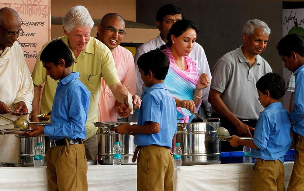 Former US President Bill Clinton serves food to a schoolboy at a kitchen run by Akshaya Patra Foundation, a non-governmental organization, in Jaipur.