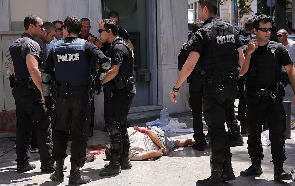 Nikos Maziotis lays wounded on a sidewalk, surrounded by police after a shootout at the tourist area of Monastiraki in central Athens. Greek police arrested one of the country`s most wanted men — a fugitive convicted of terrorism — during a shootout Wednesday in Athens` central tourist district that left four people wounded, authorities said. 