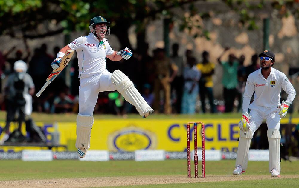 South African batsman Dean Elgar celebrates scoring a century as Sri Lanka wicketkeeper Dinesh Chandimal watches during the first day of the first test cricket match between Sri Lanka and South Africa in Galle, Sri Lanka.