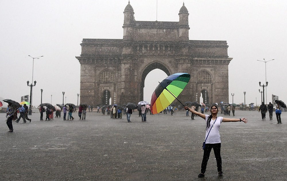 People enjoy at The Gateway of India during heavy rains in Mumbai.