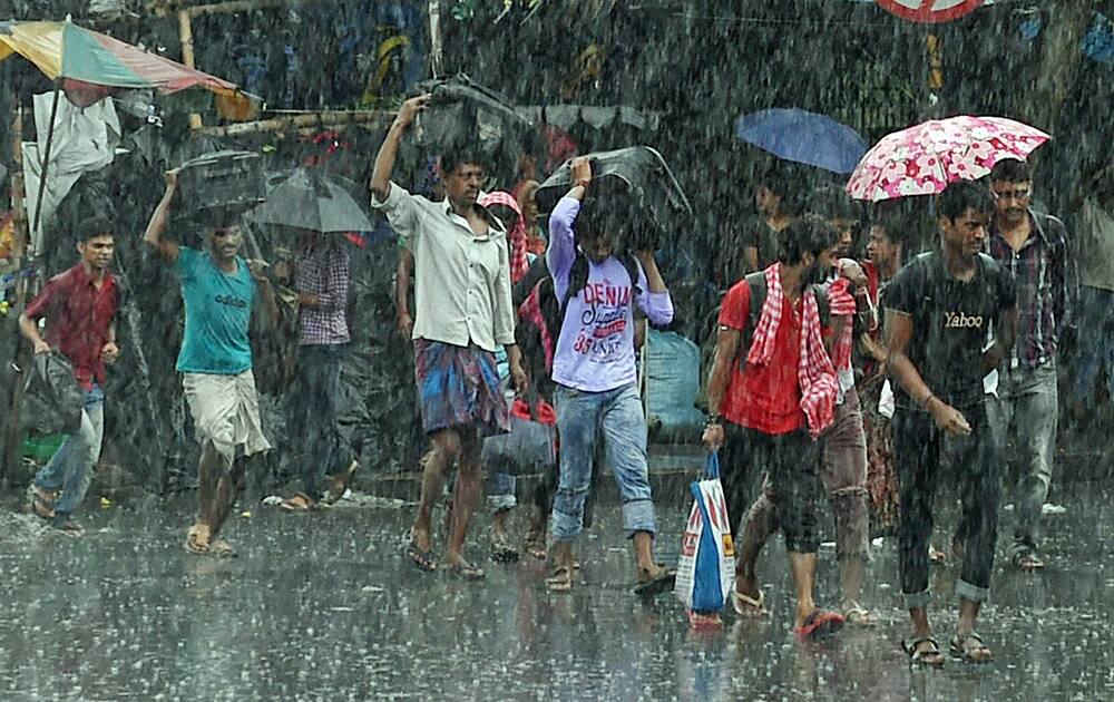 People cross a road in heavy rains in Kolkata.