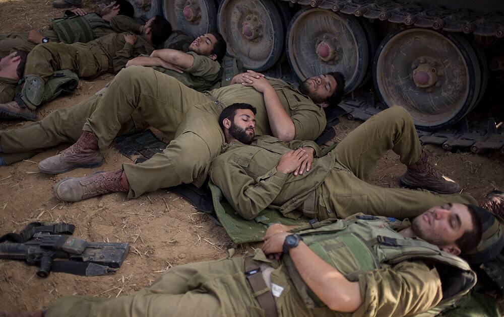 Israeli soldiers sleep beside their military vehicle near the Israel Gaza Border.