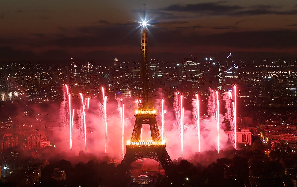 Bastille Day fireworks explode over the Seine river next to the Eiffel Tower in Paris.