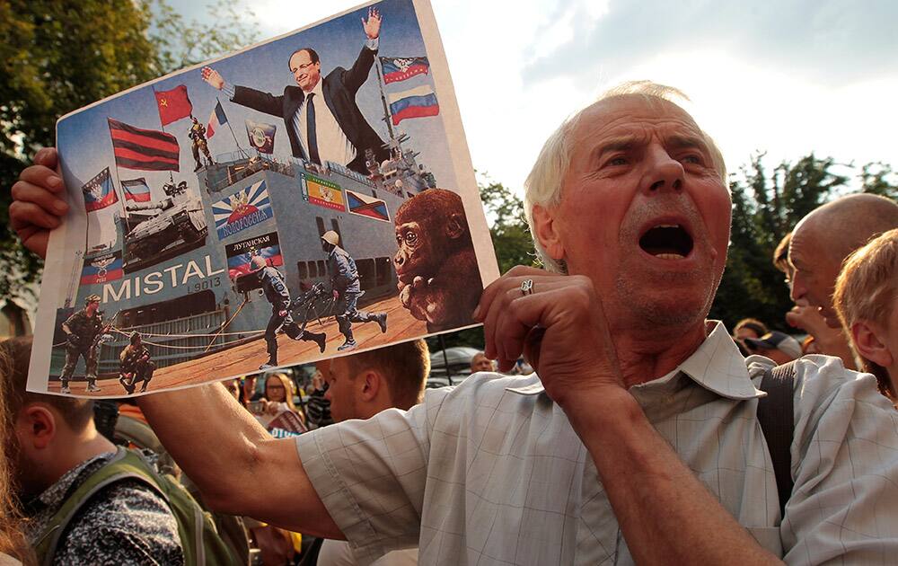 Ukrainians shout slogans during a protest against the sale by France to Russia of Mistral amphibious assault ships, in Kiev, Ukraine.