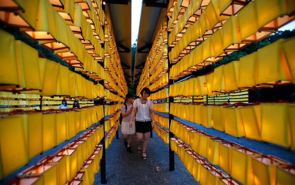 Women walk in front of rows of paper lanterns during the festival of 