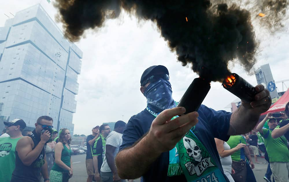 A Seattle Sounders supporter burns smoke devices during the traditional `March to the Match` before an MLS soccer match between Seattle Sounders FC and the Portland Timbers, in Seattle. 