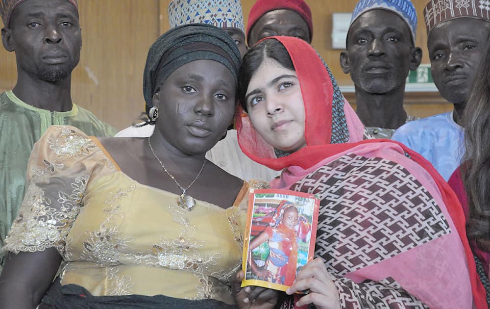 Pakistani activist Malala Yousafzai who survived being shot by the Taliban because she advocated education for girls, holds a picture of kidnapped schoolgirl Sarah Samuel with her mother Rebecca Samuel, during a visit to Abuja, Nigeria.